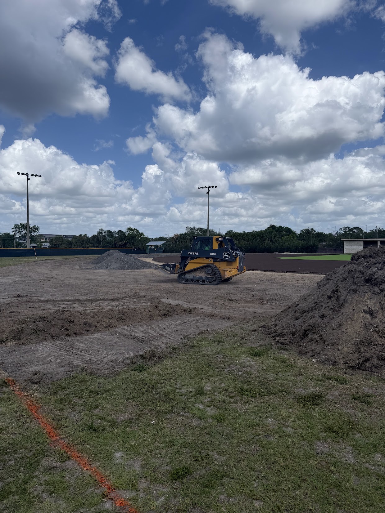 Track loader grading the dirt infield of a baseball field before turf goes down